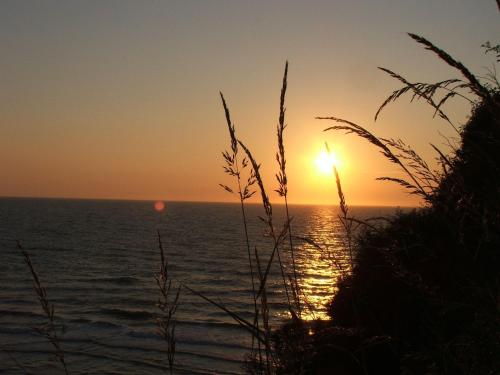 a sunset over the ocean with the sun in the sky at Y Caban at Wig Farm near Llangrannog in Llandysul