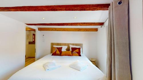 ein Schlafzimmer mit einem weißen Bett und orangefarbenen Kissen in der Unterkunft Résidence de l'ancien relais in Colmar
