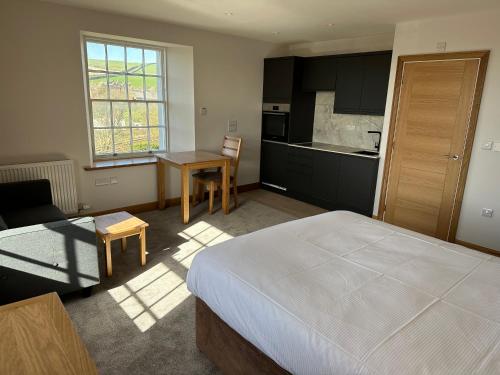 a bedroom with a bed and a table and a kitchen at Grindal - Executive Apartment Hotel in St Bees
