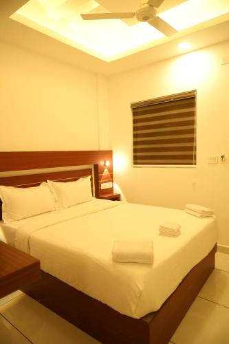 a bedroom with a bed with white sheets and a ceiling at Misty Avenue Premium Rooms in Anachal