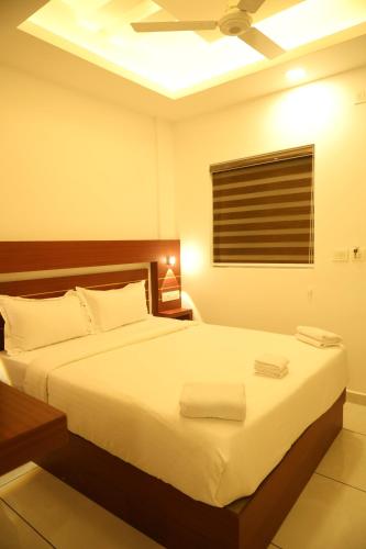 a bedroom with a bed with white sheets and a ceiling at Misty Avenue Premium Rooms in Anachal