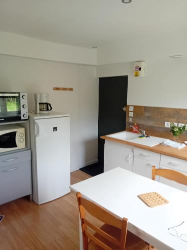 een keuken met witte apparatuur en een tafel met stoelen bij Chambre équipée in Languidic