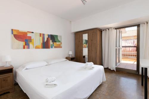 a bedroom with a large white bed and a window at ApartEasy - Atic Sants in Barcelona