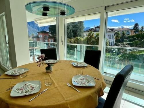 einen Esstisch mit Stühlen und ein großes Fenster in der Unterkunft Residenza Monte Verità, apt nr 10 in Ascona