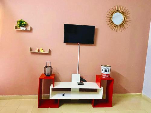 uma sala de estar com televisão numa parede cor-de-rosa em Cool meuble em Ouagadougou