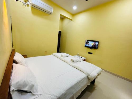 een ziekenhuiskamer met een bed en een tv aan de muur bij Kihim Paradise Beach & Resort in Alībāg