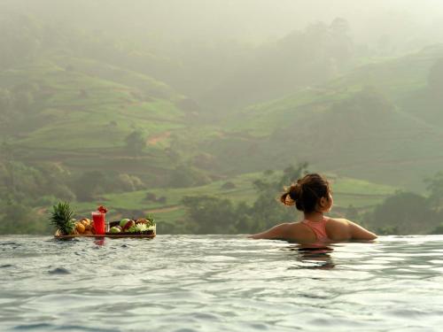 a woman in the water with a tray of fruit at The Grand Cliff Resort Munnar in Viripara