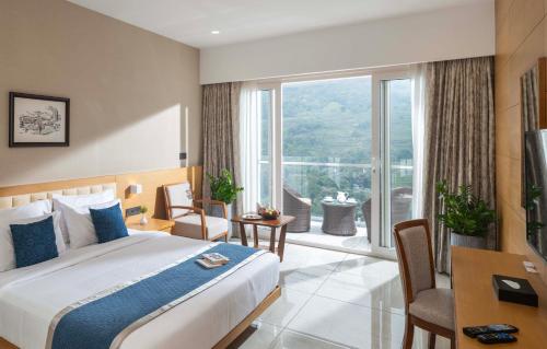 a hotel room with a bed and a large window at The Grand Cliff Resort Munnar in Viripara