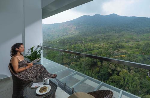 a woman sitting at a table with a plate of food at The Grand Cliff Resort Munnar in Viripara