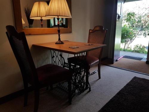 a dining room table with two chairs and a lamp at Langford Executive Apartments in Bristol