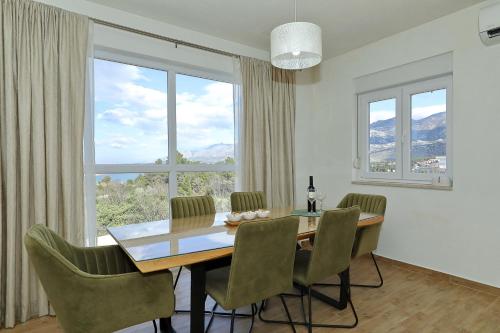 a dining room with a table and chairs and windows at Temida in Rovanjska