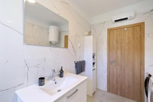 a white bathroom with a sink and a mirror at Temida in Rovanjska
