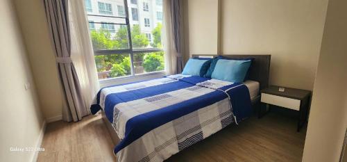 een slaapkamer met een bed met blauwe kussens en een raam bij An Na Park Hotel Room - Chiang Mai in Chiang Mai