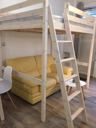 une chambre avec lits superposés, un canapé jaune et une échelle dans l'établissement Jolie studio à deux pas du centre historique, à Montpellier