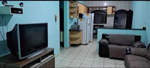 een woonkamer met een flatscreen-tv en een bank bij Aluga-se casa com Piscina no Guarujá in Guarujá