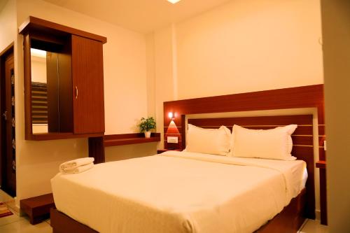 a bedroom with a large bed with a wooden headboard at Misty Avenue Premium Rooms in Anachal