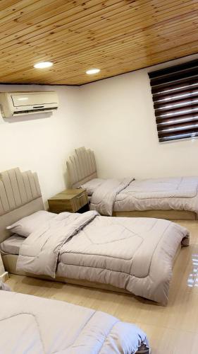 Schlafzimmer mit 3 Betten und Holzdecke in der Unterkunft الكرك زحوم in Kerak