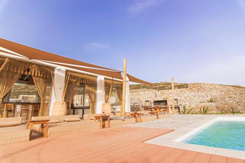 a building with a swimming pool and a patio with benches at Villa Poppy private pool by opus in Mýkonos City