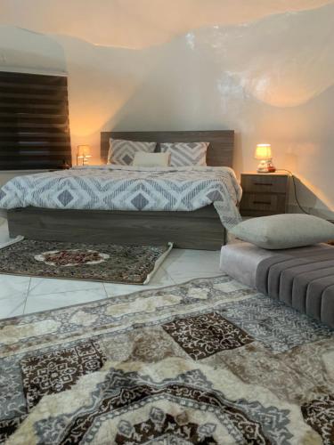 a bedroom with a bed and two rugs at Auberge oued Illij in Atar