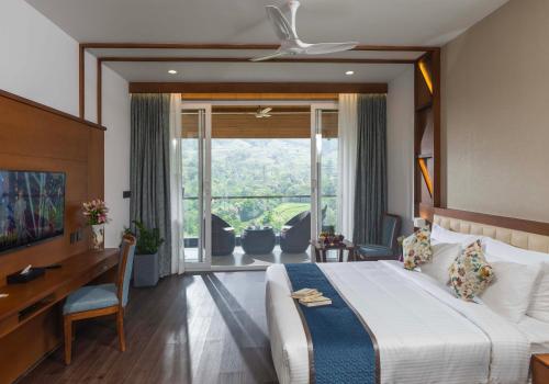 a bedroom with a bed and a desk and a large window at The Grand Cliff Resort Munnar in Viripara