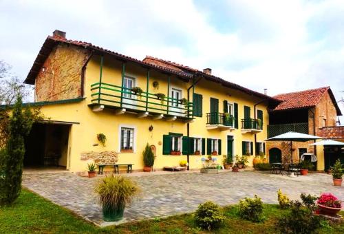 a large yellow building with green shutters and a patio at Casa relax immersa nel verde della natura in Casalborgone