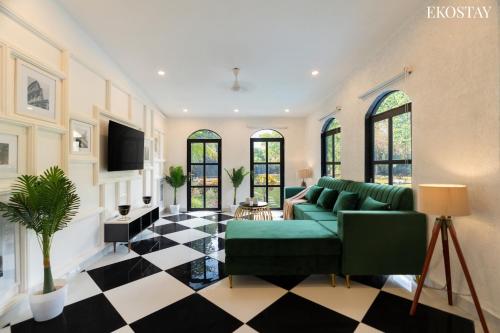 a living room with a green couch and a checkered floor at EKOSTAY Luxe - Casa Roma in Alibaug