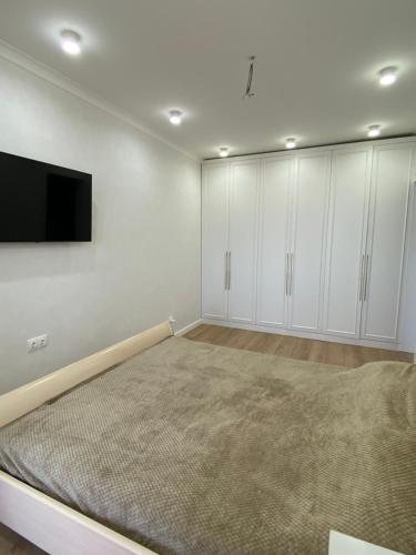 1 dormitorio con 1 cama y TV de pantalla plana en жилой комплекс AMAN en Prigorodnyy