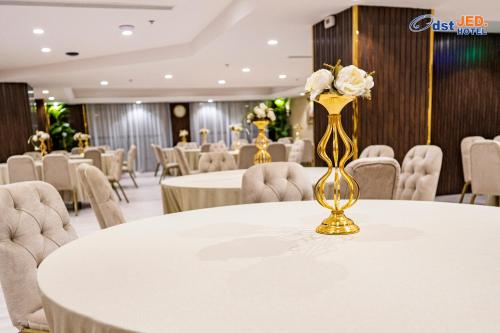 a banquet hall with white tables and chairs and a vase with flowers at Odst Jeddah in Jeddah
