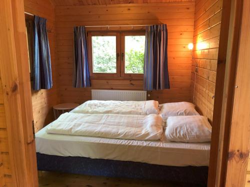 Cama en habitación de madera con ventana en Sfeervolle blokhut met fijne buitenruimte @ Veluwe en Epe