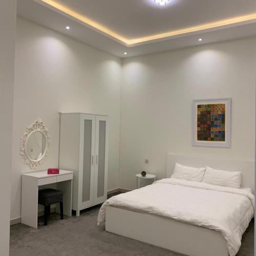 a white bedroom with a bed and a mirror at شاليهات أوريجامي in Buraydah