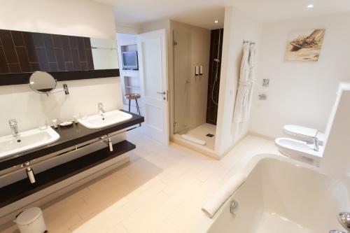 a bathroom with two sinks and a tub and a shower at Hotel Le Verger Maelvi in Grimaud
