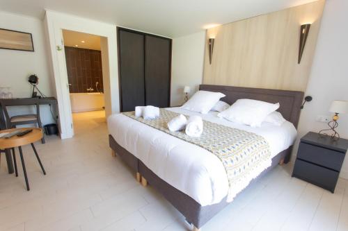 a bedroom with a large bed with white sheets and white pillows at Hotel Le Verger Maelvi in Grimaud