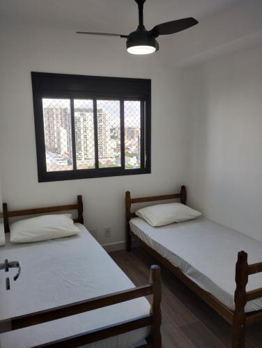 2 Betten in einem Zimmer mit Fenster in der Unterkunft Piscine Resort Brás in São Paulo