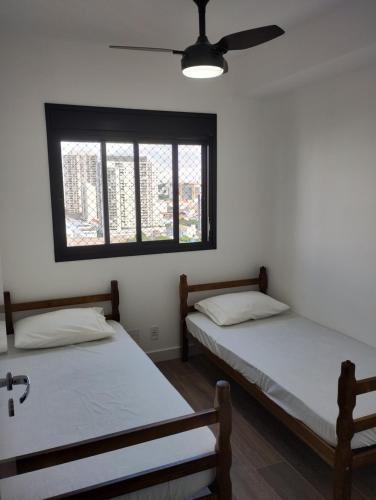 two beds in a room with a window at Apto Resort Brás Piscina, Ar-condicionado in São Paulo