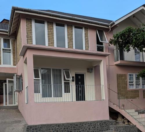 a pink house with a balcony at Remarkable 3-Bed House in Freetown in Freetown