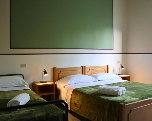 two beds in a room with a large greenboard on the wall at Ostello e Camere Private Prima Luce Foresteria in Giulianova
