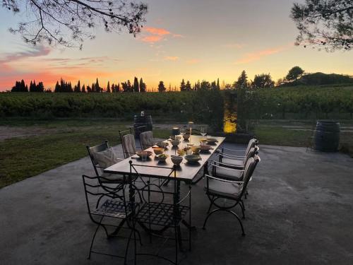 une table avec des chaises autour de celle-ci et le coucher du soleil en arrière-plan dans l'établissement Luxury Provencal Villa amidst own vinyards, à Caromb