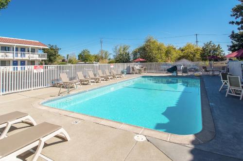 a swimming pool with chaise lounge chairs at Motel 6-Redding, CA - South in Redding