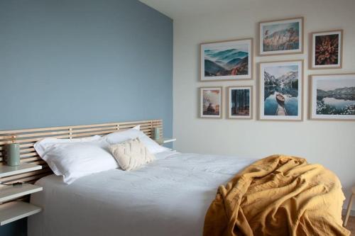 ein Schlafzimmer mit einem weißen Bett mit Bildern an der Wand in der Unterkunft Duplex 6 personnes, vue panoramique sur lac in Malbuisson