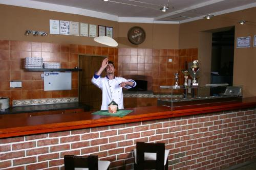 a man standing behind a bar with his hand in the air at Penzion FAJN *** in Pardubice