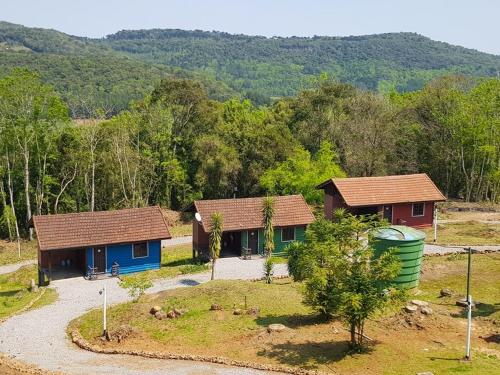 two houses in a field with trees in the background at Pousada Villa da Uva in Gramado