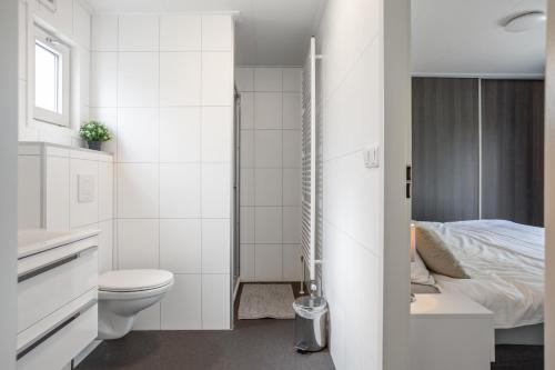 een witte badkamer met een toilet en een bed bij Chalet 41 met twee badkamers in Oosterwolde