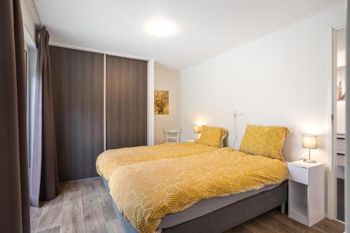 een slaapkamer met een bed met een gele sprei bij Chalet 41 met twee badkamers in Oosterwolde