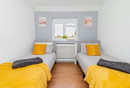 two beds in a room with yellow and grey at Eastleigh Serviced Apartment in Chandlers Ford