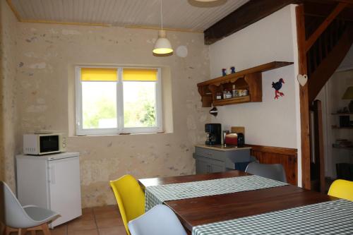a kitchen with a dining room table and yellow chairs at L'autre Monde Chambres D'hôtes in Faverolles