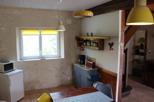 a small kitchen with a table and a window at L'autre Monde Chambres D'hôtes in Faverolles