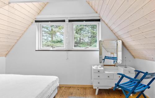 een slaapkamer met een bed en een spiegel en een blauwe stoel bij Pet Friendly Home In Saltum With House A Panoramic View in Saltum