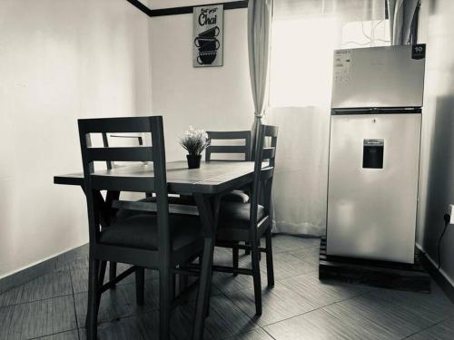 a table and chairs in a kitchen with a refrigerator at Chayil Loft Mulago in Kampala