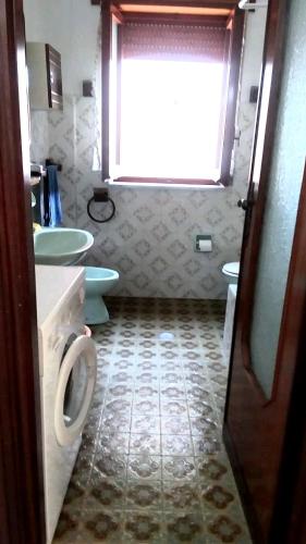 baño con aseo y lavabo y ventana en Appartamento Rione Euro, en Gioiosa Ionica