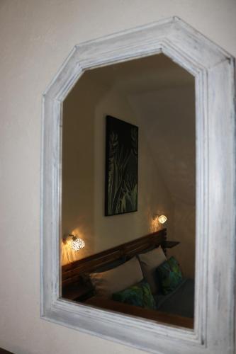 a mirror in a white frame on a wall at L'autre Monde Chambres D'hôtes in Faverolles